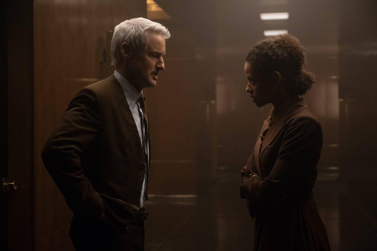 Still image featuring Owen Wilson and Gugu Mbatha Raw in period clothing looking at each other in a library