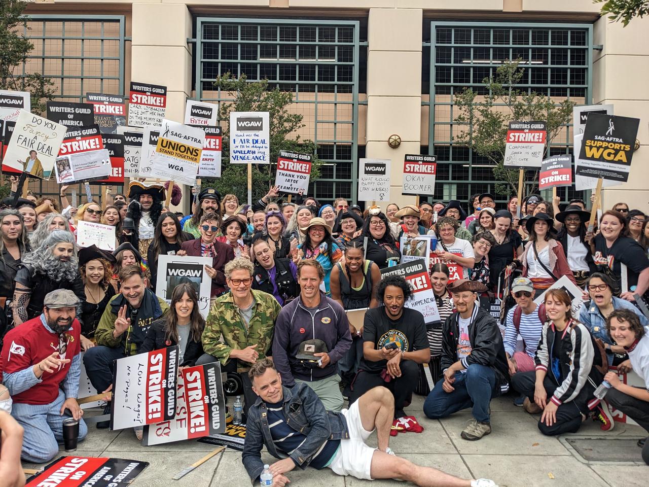 Group photograph of strikers, fans, writers, and cast of Our Flag Means Death