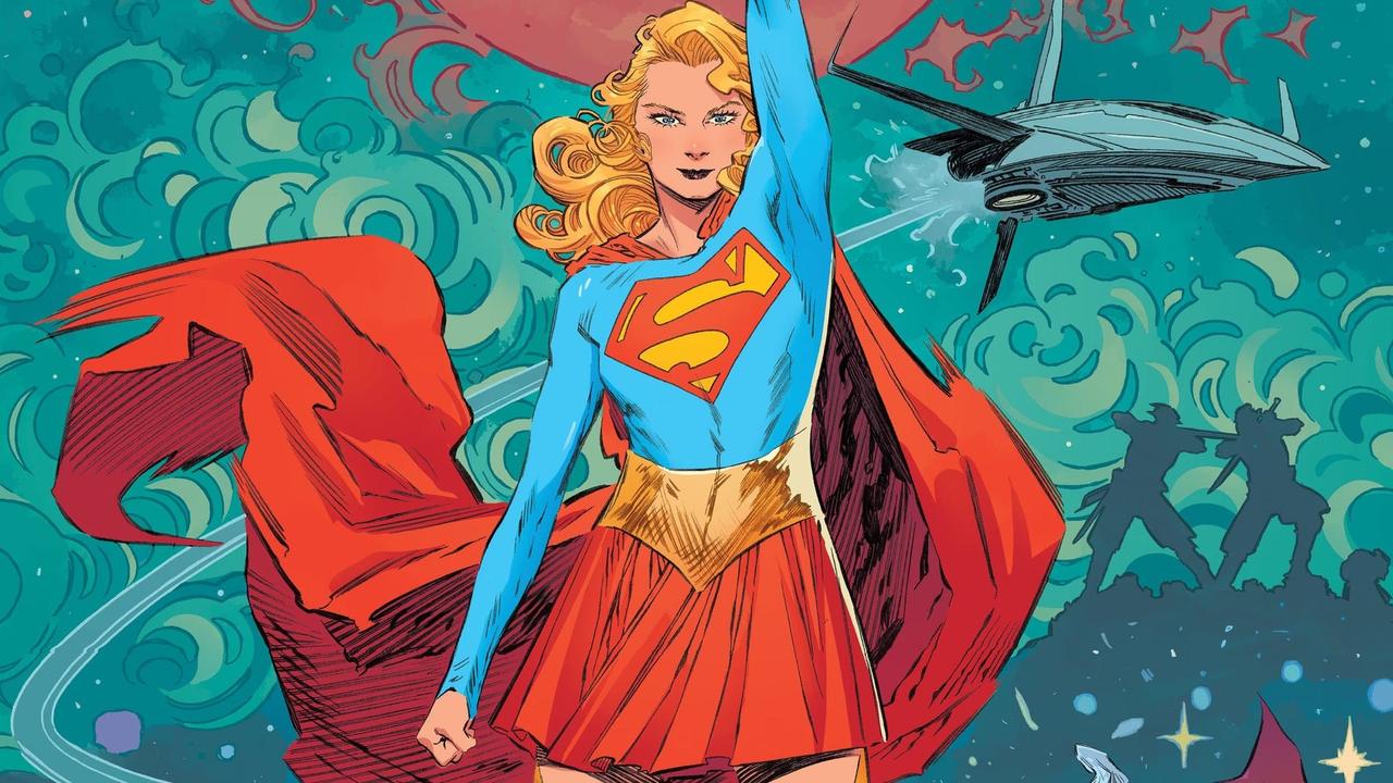 Supergirl stands with her arm raised